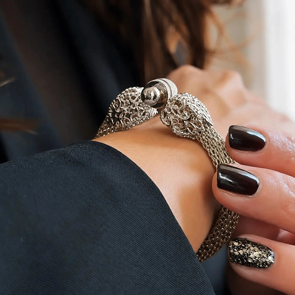 Bracelet MENILMONTANT Argenté porté au poignet, détail du fermoir sous une manche de veste noire