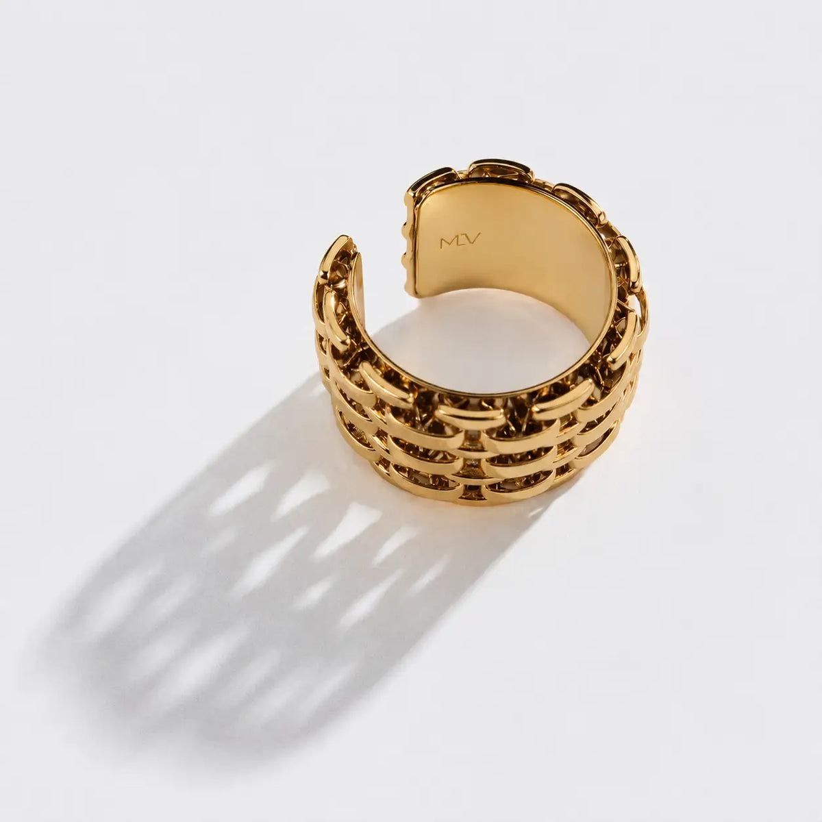 Bague Montorgueil dorée sur fond clair, ombre ajourée et logo MLV gravé à l’intérieur.