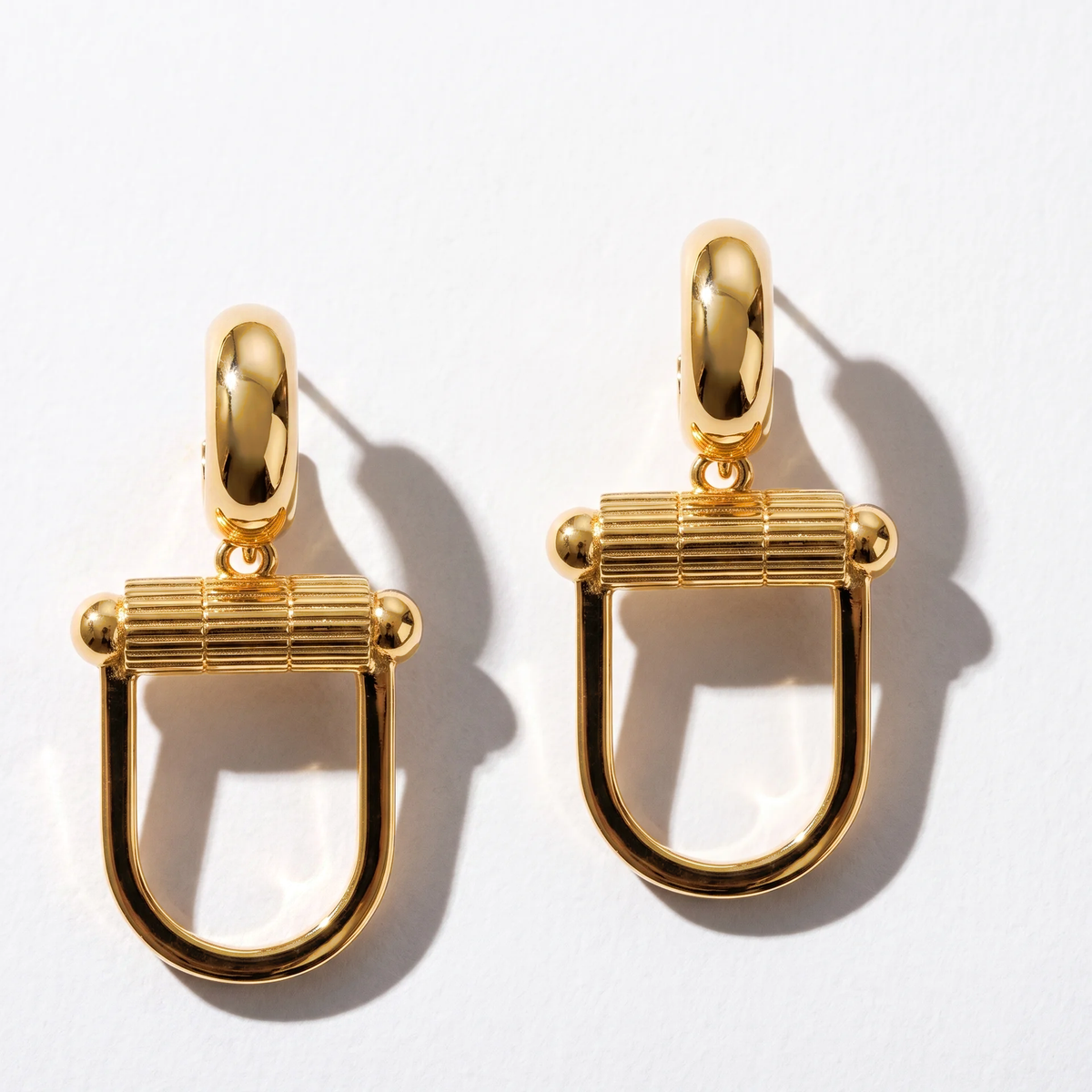 Paire de boucles Montorgueil dorées sur fond clair.